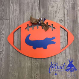 Orange football-shaped wall sign with a blue alligator and ribbon bow