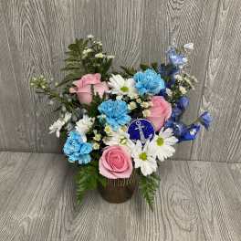 Pink roses and blue carnations in a vase with white daisies.