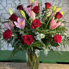 Red roses and pink lilies in a clear glass vase