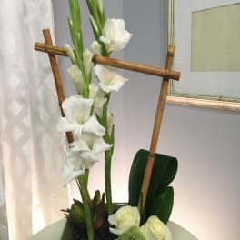 Tall white gladiolus arrangement in a green square vase with bamboo accents