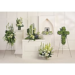 Sympathy floral collection in white and green with standing sprays and a cross-shaped arrangement.
