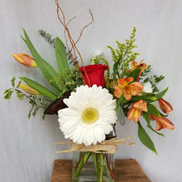 Mixed bouquet in a glass vase with a red rose, white gerbera, and orange lilies
