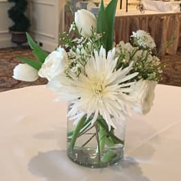 White floral arrangement in a clear glass vase on a table