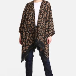Woman modeling a brown and black leopard print poncho with fringe hem