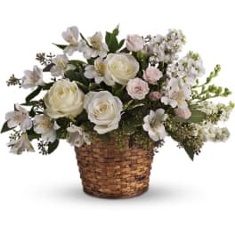 White roses and pale flowers arranged in a wicker basket