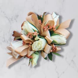 Cream rose bouquet with peach ribbon loops on a light marble surface