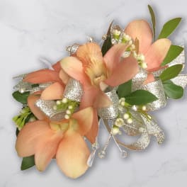 Peach orchid corsage with silver ribbon and green leaves