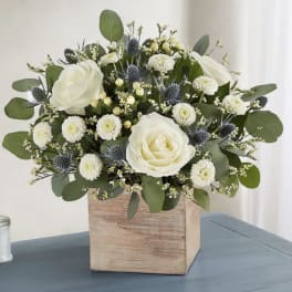 White roses and small white blooms in a wooden box