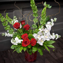 Red roses and white orchids arranged in a red glass vase