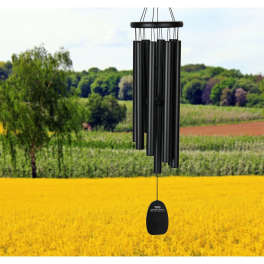 Black wind chime hanging outdoors over a field