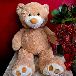 Plush teddy bear beside a potted plant wrapped with red tinsel