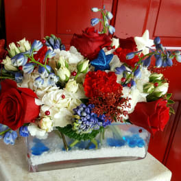 Red roses and white flowers arranged in a clear rectangular vase