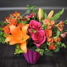 Bouquet of orange lilies and pink roses in a magenta vase