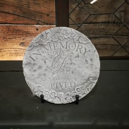 Round memorial plaque with the words In Memory of a life so beautifully lived