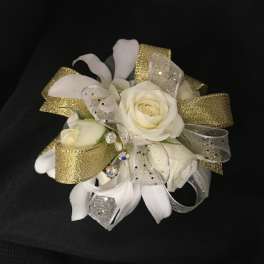 White rose corsage with gold and silver ribbon on a black background
