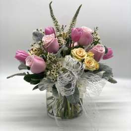 Pink and yellow roses with tulips in a glass vase