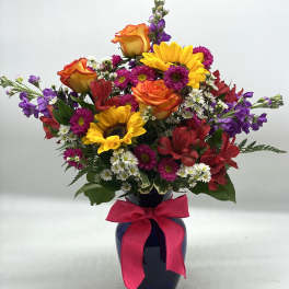 Colorful bouquet with sunflowers, roses, and daisies in a dark vase