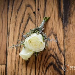 White rose boutonniere with small purple filler flowers