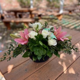 Pink lilies and white roses in a low black container