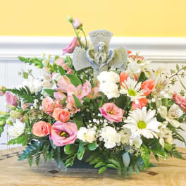 Pastel floral arrangement with a small angel figurine centerpiece