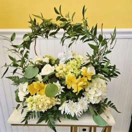 White and yellow floral arrangement with a leafy arch
