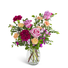 Mixed bouquet of pink roses and red and peach carnations in a clear glass vase