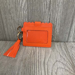 Orange card holder with a tassel on a wood surface