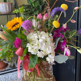 Mixed bouquet with hydrangea, sunflower, orchids, and pink tulips in a glass vase