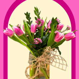 Pink tulips in a glass vase with a twine bow