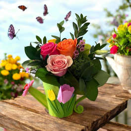 Pink, orange, and peach roses in a green tulip-shaped container