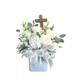 White floral arrangement with a moss cross in a square vase and sheer white bow