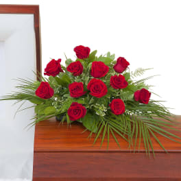 Red rose casket spray arranged on a polished wooden casket