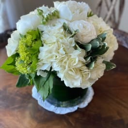 White floral arrangement in a dark vase with green accents