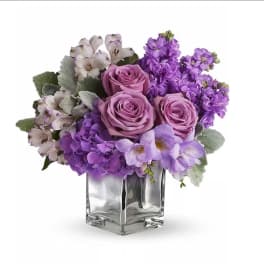 Purple bouquet of roses, hydrangeas, and alstroemeria in a glass vase