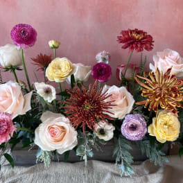 Mixed bouquet of pale roses and colorful blooms in a low arrangement