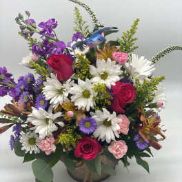 Mixed bouquet of roses, daisies, and purple flowers in a vase