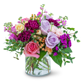 Mixed bouquet of pink, lavender, and purple roses in a glass vase