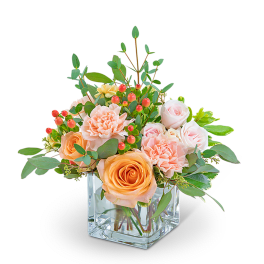 Peach and blush roses with carnations in a clear square vase