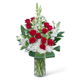 Red roses and white flowers arranged in a clear glass vase
