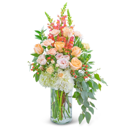 Peach roses and pink snapdragons in a clear glass vase