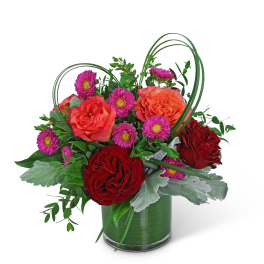 Bouquet of red and orange roses with purple daisies in a glass vase