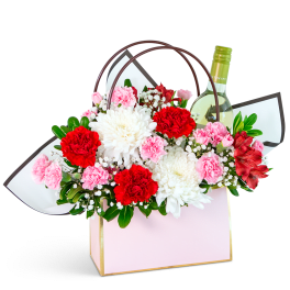 Gift bag with red and pink flowers and a wine bottle