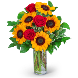Bouquet of red roses and yellow sunflowers in a clear glass vase