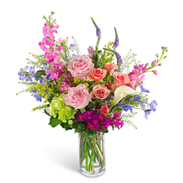 Mixed bouquet of pink roses, calla lily, and purple flowers in a glass vase