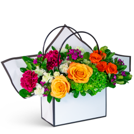 Bright mixed flower arrangement in a white handled gift box