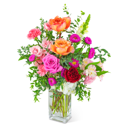 Mixed bouquet of roses, carnations, and alstroemeria in a clear glass vase