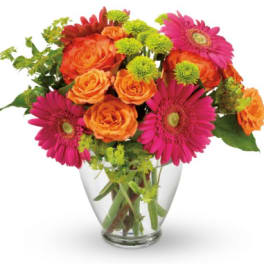 Bouquet of orange roses and pink gerbera daisies in a clear glass vase