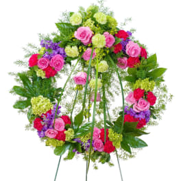 Bright standing wreath of pink roses, red carnations and green blooms on a metal easel