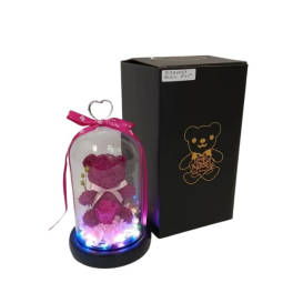 Pink teddy bear and artificial rose under glass dome with lights beside black gift box