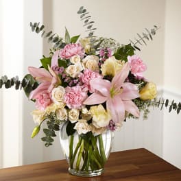 Pink lilies and roses arranged in a clear glass vase
